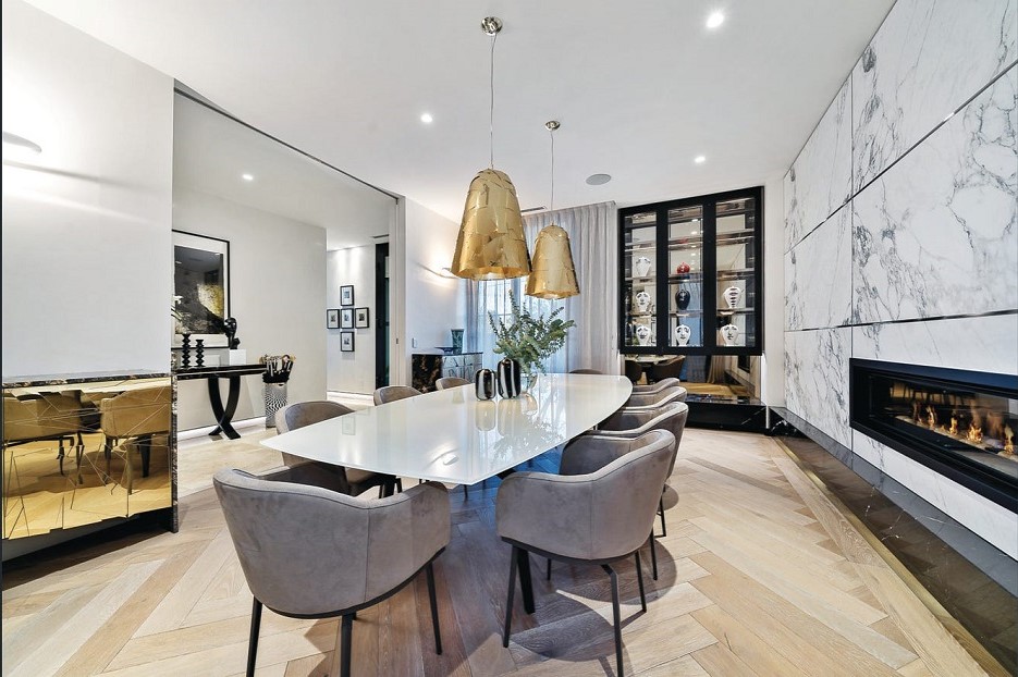 DIning room with fire place one and parquetry blonde wood floors in Toorak mansion